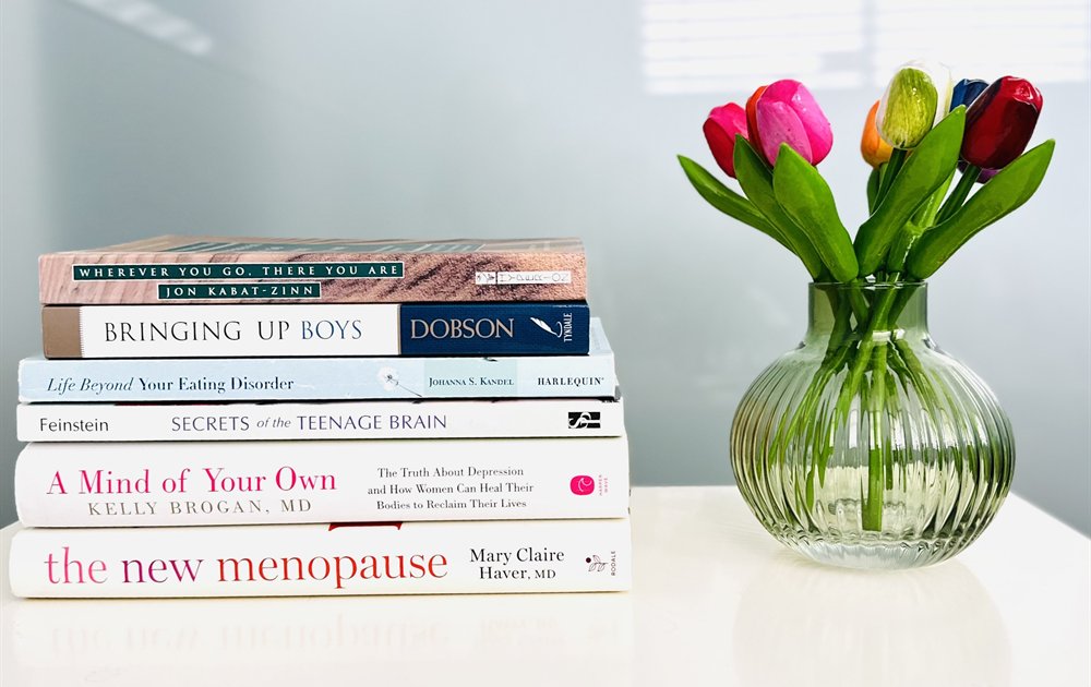Therapy and wellness books beside colorful tulips in Jennifer's office